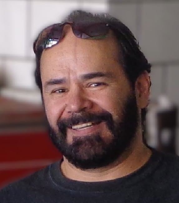 Um homem sorridente, de cabelo e barba preta, com um óculos de sol na testa. Germán A. de La Reza
