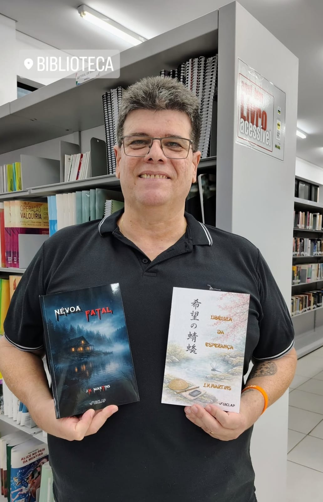 J.H. apresentando os dois livros que está lançando.